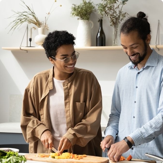 Couple wearing Avulux lenses in the kitchen cutting vegetables and smiling